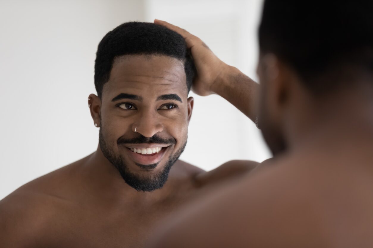A man looking at his reflection in the mirror.
